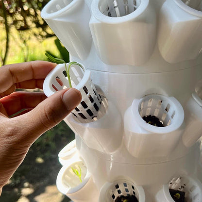 Close up of modular hydroponic tower showing removable net cups being inserted into planting ports for easy planting and maintenance