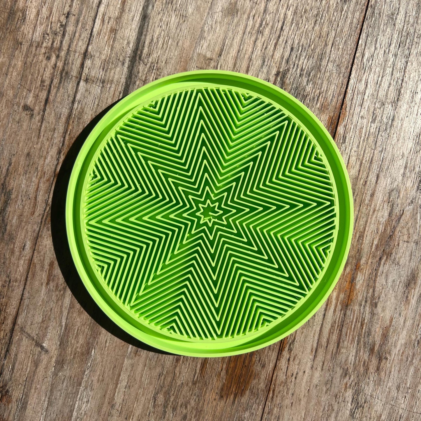 Top view of a star pattern drip tray in green, showing textured surface for water collection