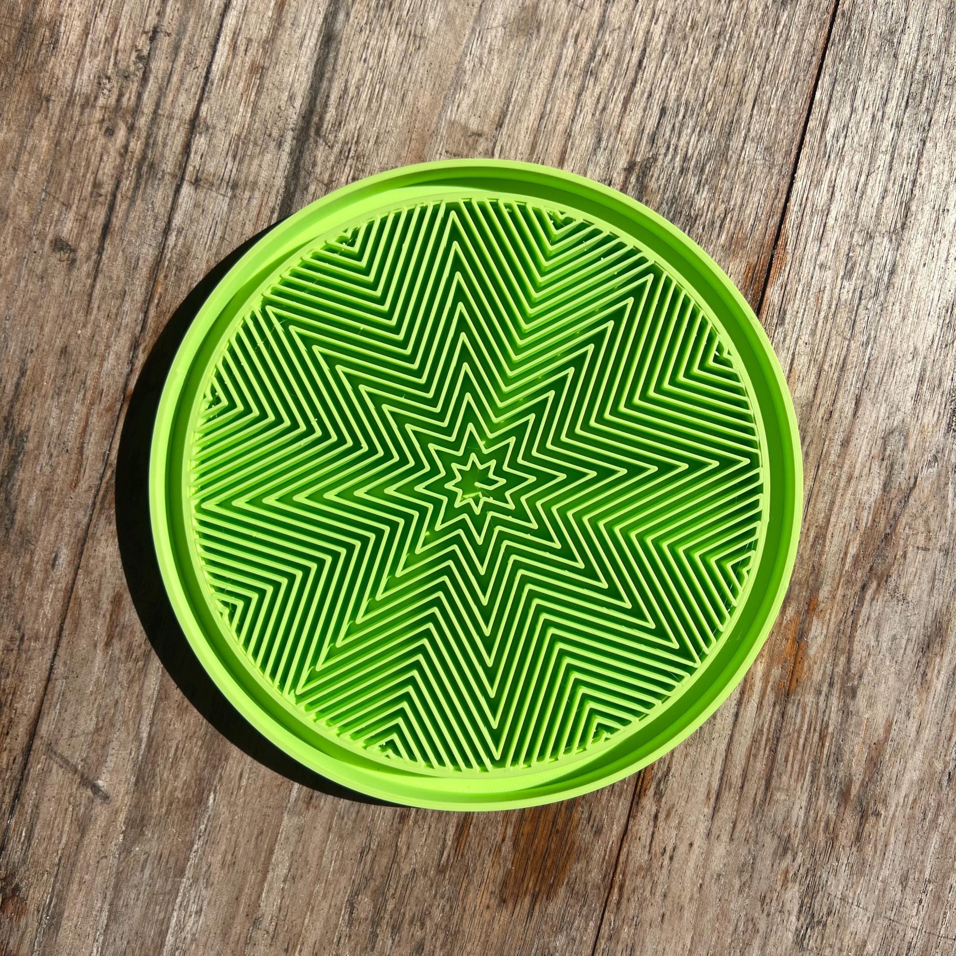 Top view of a star pattern drip tray in green, showing textured surface for water collection