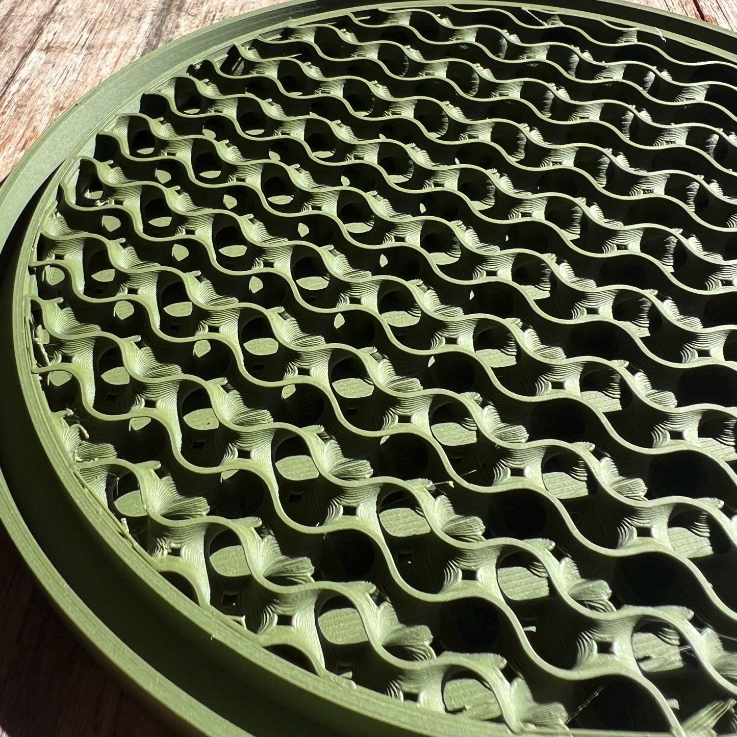 Close up of a green gyroid drip tray highlighting the repeating lattice pattern